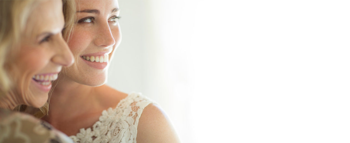 Bride smiling with her mother, both glowing with joy and emotion on the wedding day, capturing a candid moment of love, support, and celebration