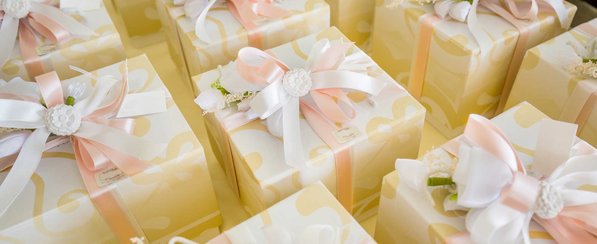 Elegant wedding gifts wrapped in cream and gold paper, finished with pink and white satin ribbons and floral embellishments