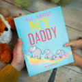 Personalised Father’s Day book titled 'All About My Daddy by Charlie', held by a father and child, featuring a playful elephant family illustration – a fun and thoughtful gift for kids to give their dad.