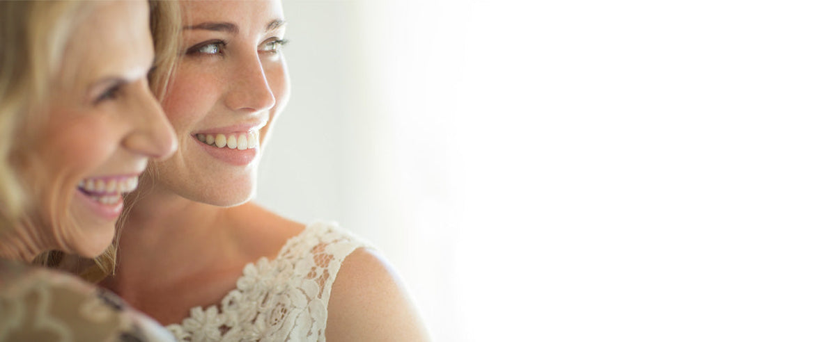 Bride smiling with her mother, both glowing with joy and emotion on the wedding day, capturing a candid moment of love, support, and celebration