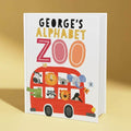 Book titled 'George's Alphabet Zoo' with a red bus illustration on a yellow background